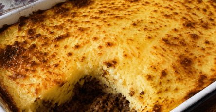 Hachis Parmentier gratiné maison servi dans un plat familial, avec une couche de purée dorée au fromage, une viande hachée fondante dessous et une texture crémeuse visible à la cuillère.