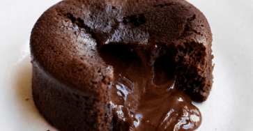 Moelleux au chocolat cœur fondant servi chaud dans une assiette, ouvert à la cuillère avec un cœur de chocolat coulant, une texture moelleuse et une surface légèrement craquelée.