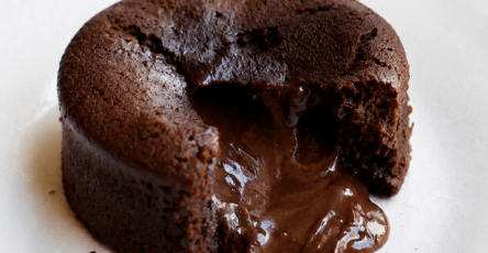 Moelleux au chocolat cœur fondant servi chaud dans une assiette, ouvert à la cuillère avec un cœur de chocolat coulant, une texture moelleuse et une surface légèrement craquelée.