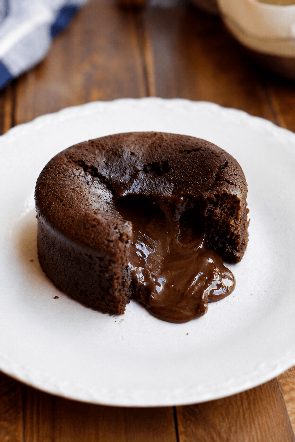 Moelleux au chocolat cœur fondant servi chaud dans une assiette, ouvert à la cuillère avec un cœur de chocolat coulant, une texture moelleuse et une surface légèrement craquelée.