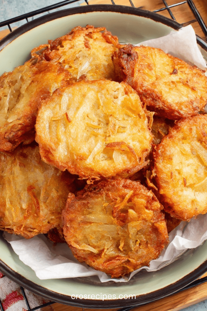 Beignets d’oignons croustillants dorés à la poêle, préparés avec une pâte légère à la farine, œuf, eau et levure, servis chauds.