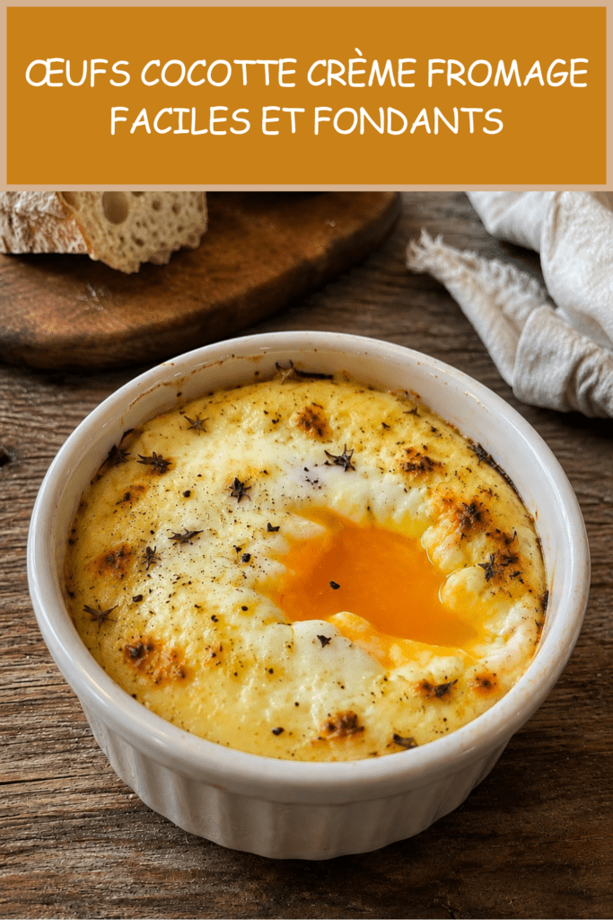 Œufs cocotte crème fromage servis dans des ramequins individuels, avec un jaune coulant, une crème onctueuse, du fromage fondu et quelques herbes fraîches sur le dessus.