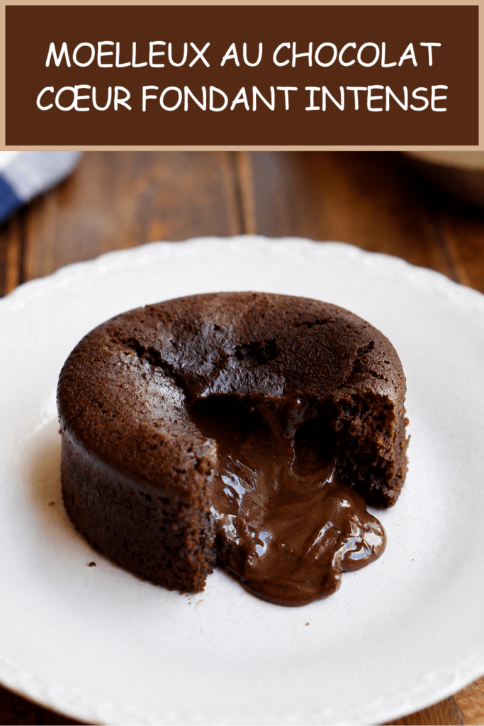 Moelleux au chocolat cœur fondant servi chaud dans une assiette, ouvert à la cuillère avec un cœur de chocolat coulant, une texture moelleuse et une surface légèrement craquelée.
