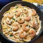 Pâtes crémeuses aux crevettes façon Alfredo servies dans une assiette creuse, avec sauce parmesan, persil frais et crevettes dorées