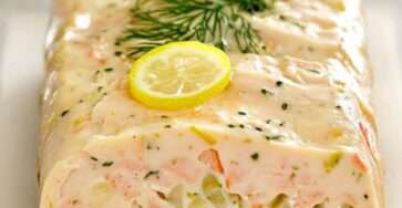 Terrine de poisson maison aux légumes, poisson blanc et saumon, coupée en tranches fraîches, servie avec sauce citronnée et herbes fraîches.