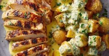 Blancs de poulet grillés coupés en tranches, servis avec des pommes de terre dorées et une sauce crémeuse aux herbes fraîches.