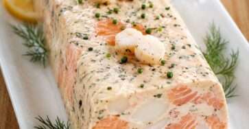 Terrine de saumon et noix de Saint-Jacques tranchée, servie froide avec sauce citronnée et herbes fraîches