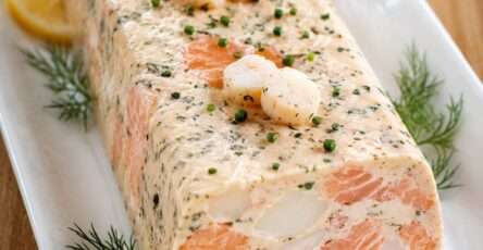 Terrine de saumon et noix de Saint-Jacques tranchée, servie froide avec sauce citronnée et herbes fraîches