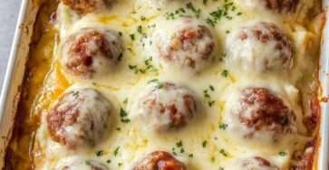 Gratin de purée avec boulettes de viande, crème et fromage fondu doré dans un plat familial chaud et gourmand