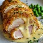 Cordon bleu de poulet doré et croustillant coupé en deux avec fromage fondu coulant et sauce crémeuse au fromage