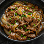Sauté de bœuf et d’oignons à la chinoise servi avec une sauce brillante, des lamelles de bœuf tendres, des oignons fondants et du riz blanc.