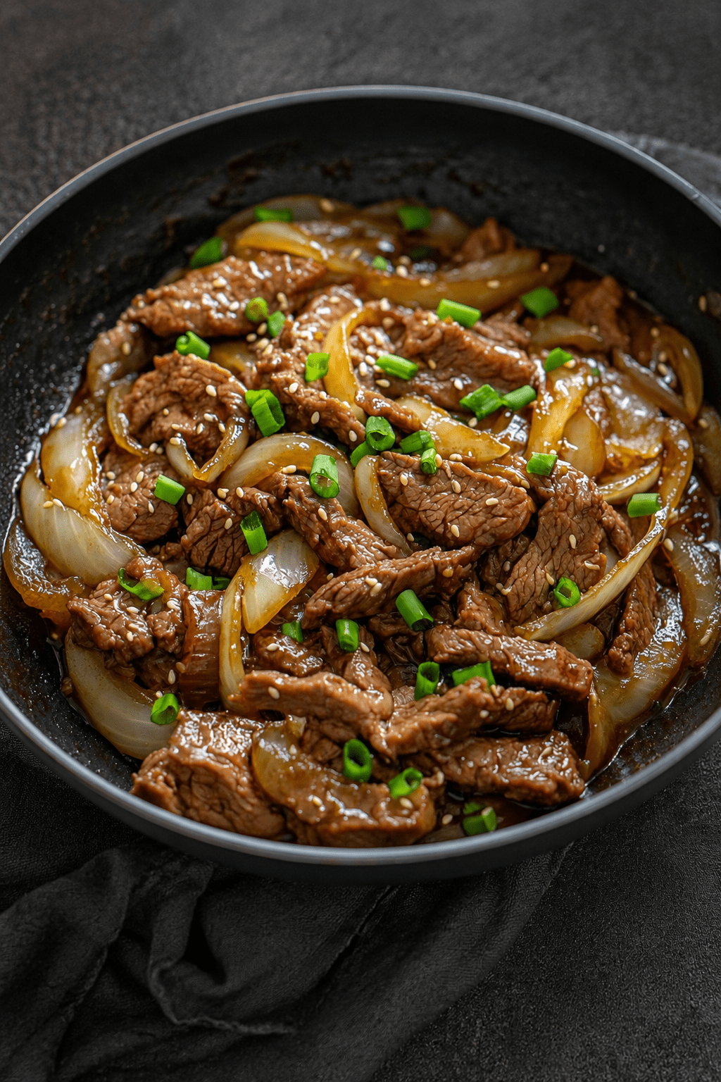 Sauté de bœuf et d’oignons à la chinoise servi avec une sauce brillante, des lamelles de bœuf tendres, des oignons fondants et du riz blanc.
