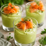 Verrines de mousse d’avocat crémeuse garnies de lamelles de saumon fumé, décorées d’aneth et servies bien fraîches.