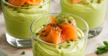 Verrines de mousse d’avocat crémeuse garnies de lamelles de saumon fumé, décorées d’aneth et servies bien fraîches.