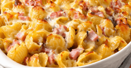Gratin de coquillettes au jambon et gruyère râpé bien doré, servi chaud dans un plat familial avec une texture crémeuse.