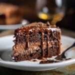 Gâteau au chocolat fondant nappé de ganache brillante, avec un cœur crémeux au chocolat et des copeaux de chocolat sur le dessus.
