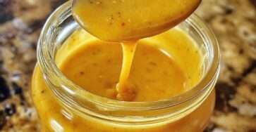 Vinaigrette miel-moutarde maison servie dans un petit pot en verre, avec une texture épaisse, brillante et dorée.