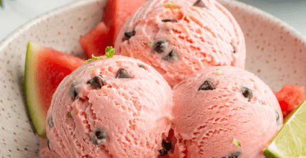Boules de glace rose à la pastèque servies dans un bol froid, avec des pépites de chocolat rappelant les graines du fruit et des morceaux de pastèque fraîche.
