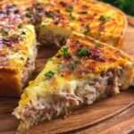 Tarte au thon crémeuse et gratinée servie en parts, avec une pâte dorée, une garniture fondante au thon et une couche de fromage gratiné.