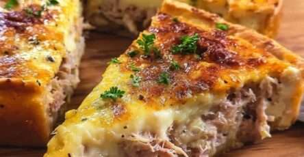 Tarte au thon crémeuse et gratinée servie en parts, avec une pâte dorée, une garniture fondante au thon et une couche de fromage gratiné.