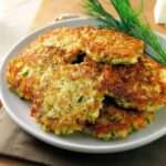 Galettes de courgettes dorées et croustillantes servies avec une sauce au yaourt, des herbes fraîches et une salade verte.