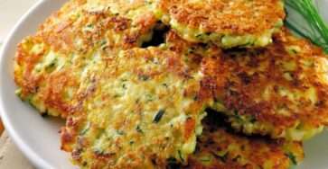 Galettes de courgettes dorées et croustillantes servies avec une sauce au yaourt, des herbes fraîches et une salade verte.