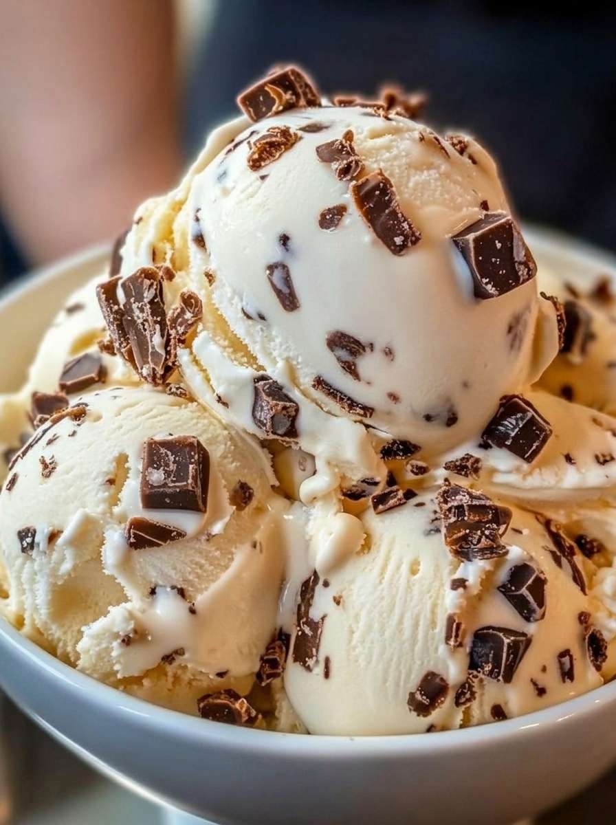 Boules de glace stracciatella maison servies dans un bol, avec une crème vanillée onctueuse et de généreux éclats de chocolat croquant.