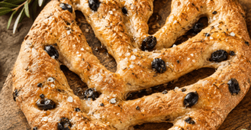 Fougasse provençale sans pétrissage, dorée et croustillante, façonnée en forme de feuille avec plusieurs entailles, garnie d’olives noires, de romarin frais et de gros sel.