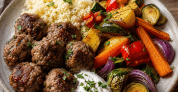 Des boulettes de bœuf épicées, une semoule légère et des légumes rôtis servis avec une sauce fraîche.