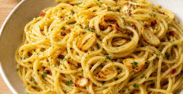 Assiette de spaghetti aglio e olio avec ail doré, persil frais, piment rouge et chapelure croustillante.