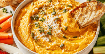 Dip chaud de courge butternut rôtie et parmesan dans un plat gratiné, servi avec du pain grillé et des crudités.