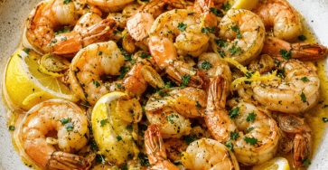 Crevettes poêlées à l’ail et au citron, nappées de beurre et parsemées de persil frais dans une poêle.