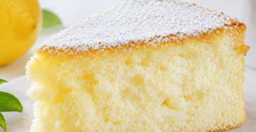 Gâteau nuage au citron très haut et aérien, légèrement doré, découpé pour révéler une mie blanche et mousseuse, décoré de sucre glace et de zestes de citron.
