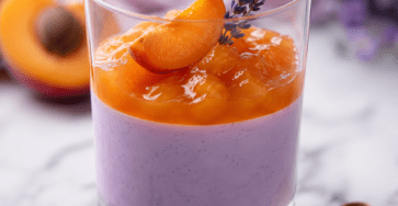 Verrines de panna cotta blanche à la lavande surmontées d’une compotée d’abricots orangée, décorées de quartiers de fruits et de lavande alimentaire.