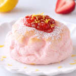 Cloud bread fraise-citron en forme de dôme rose pâle, à la texture aérienne, décoré de fraises fraîches et de fins zestes de citron.