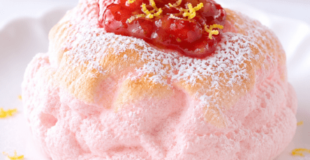 Cloud bread fraise-citron en forme de dôme rose pâle, à la texture aérienne, décoré de fraises fraîches et de fins zestes de citron.