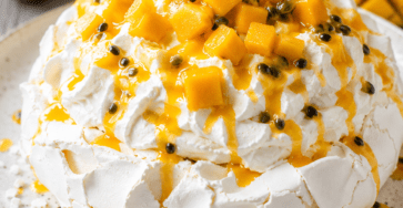 Pavlova exotique composée d’une meringue blanche craquante, de chantilly vanillée, de dés de mangue et de coulis de fruit de la passion.