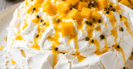 Pavlova exotique composée d’une meringue blanche craquante, de chantilly vanillée, de dés de mangue et de coulis de fruit de la passion.