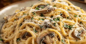 Spaghetti crémeux façon carbonara végétarienne, garnis de champignons de Paris bien dorés, de parmesan râpé, de poivre noir et de persil frais.