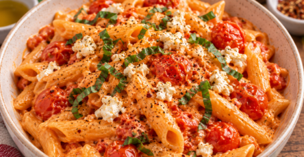 One-pot pasta crémeux à la tomate et à la feta, avec tomates cerises fondantes, ail et feuilles de basilic frais dans une grande casserole.