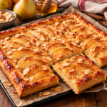Tarte fine aux poires, miel et amandes effilées sur une pâte feuilletée dorée et croustillante, garnie de fines lamelles de poires caramélisées, d'amandes grillées et d'un filet de miel brillant.