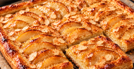 Tarte fine aux poires, miel et amandes effilées sur une pâte feuilletée dorée et croustillante, garnie de fines lamelles de poires caramélisées, d'amandes grillées et d'un filet de miel brillant.